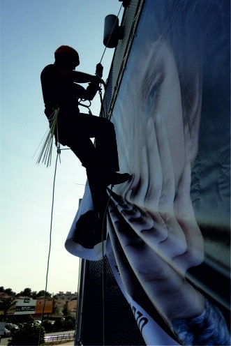 Trabajador de Rotulex instalando una de nuestras Lonas Publicitarias en Madrid