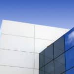 Fachada de edificio contemporáneo con paneles de composite blanco y vidrios azules en ángulo