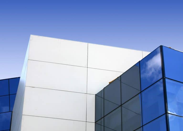 Fachada de edificio contemporáneo con paneles de composite blanco y vidrios azules en ángulo